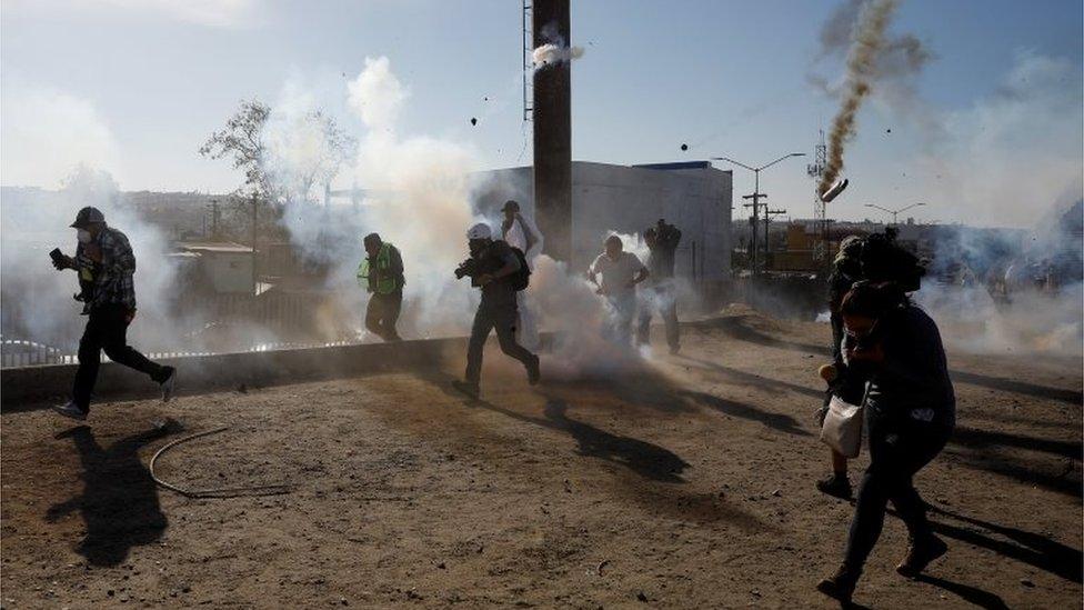 Migrants and journalists flee tear gas released by US border patrol near the fence between Mexico and the United States in Tijuana, Mexico, November 25, 2018.