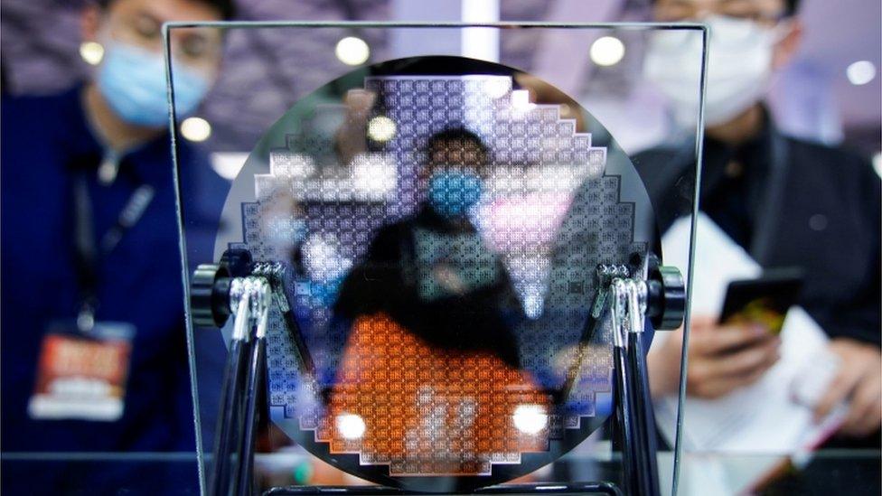 Visitors look at a display of a semiconductor device at Semicon China