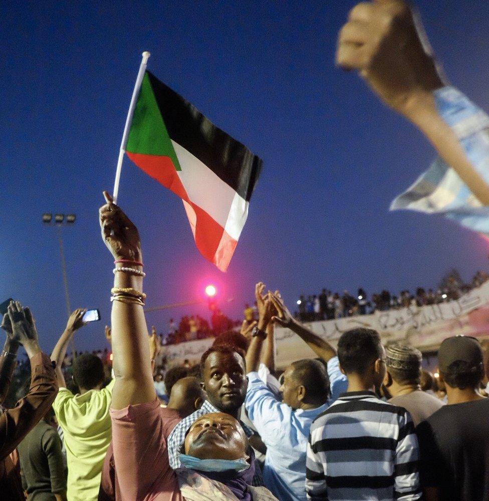 A woman holding up a Sudanese flag at a sit-in at the military HQ in Khartoum, Sudan -Sunday 7 April 2019