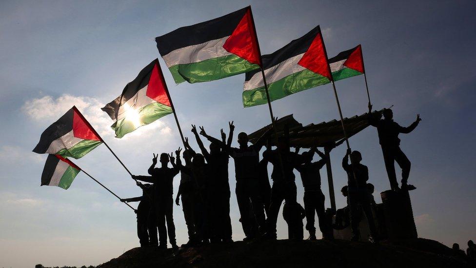 Palestinian protesters wave Palestinian flags near the Israel-Gaza border fence on 9 January 2018