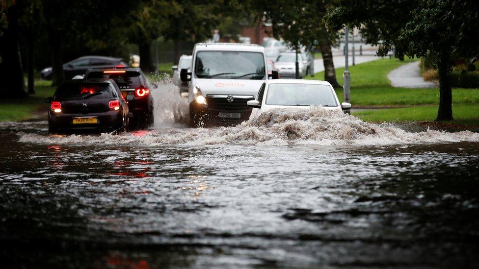 Cars attempt to pass through a flooded road in Newcastle-under-Lyme, Staffordshire, England