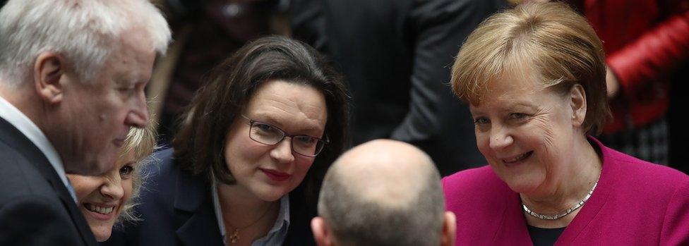 Horst Seehofer, left, Andrea Nahles, centre, and Angela Merkel, right, smile and chat around an informal table at an event