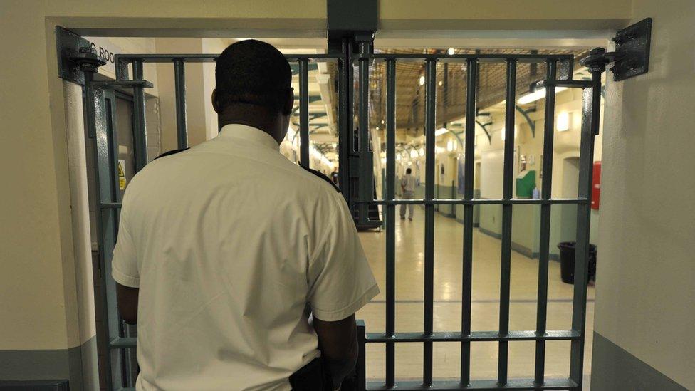 Prison officer stands at barred doors