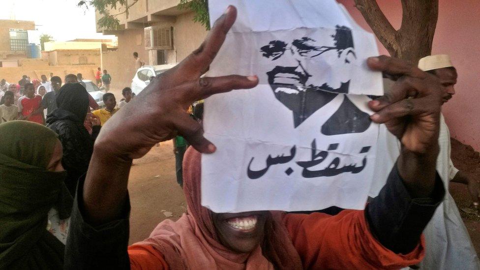 A Sudanese protester carries a portrait of President Omar al-Bashir with Arabic writing that reads "Down and that is all" during an anti-government demonstration east of the capital Khartoum on 9 February 2019