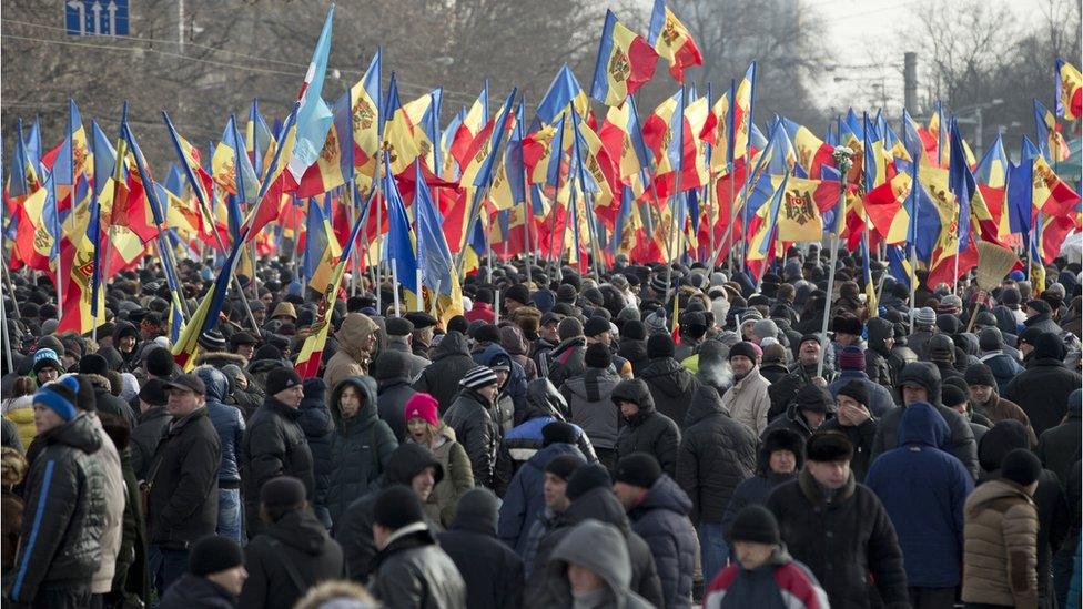 People hold flags during a large protest in Chisinau, Moldova, Sunday, Jan. 24, 2016