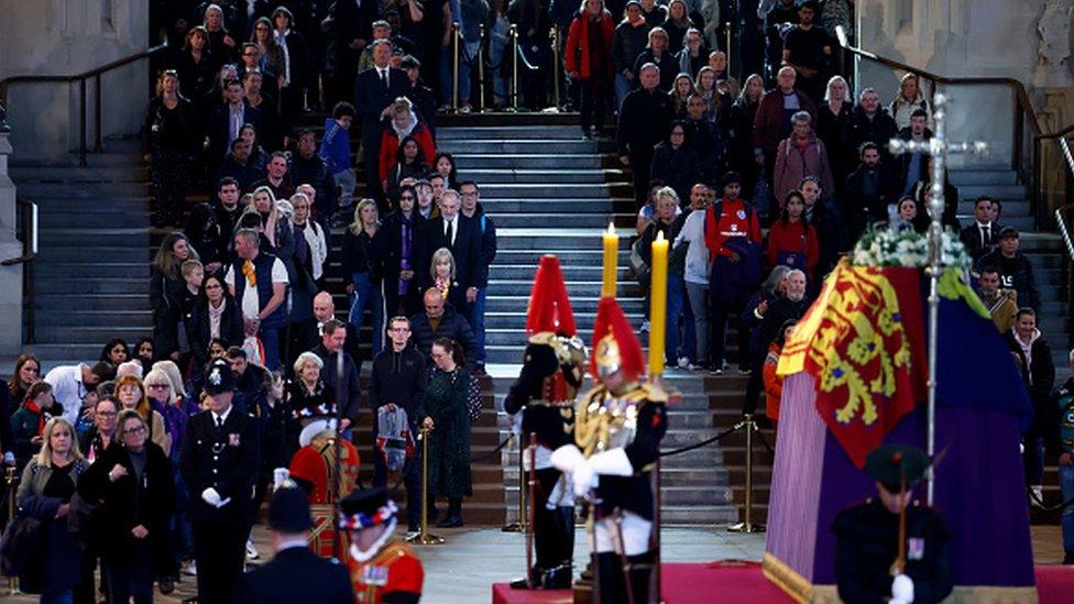 Members of the public pay their respects as they pass Queen Elizabeth II's flag-draped coffin