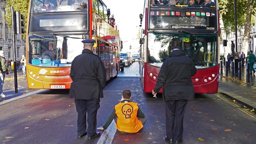 A Just Stop Oil activist sits in the middle of Whitehall in Westminster, London