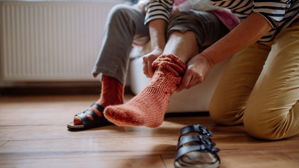 woman putting sitting man's sock on