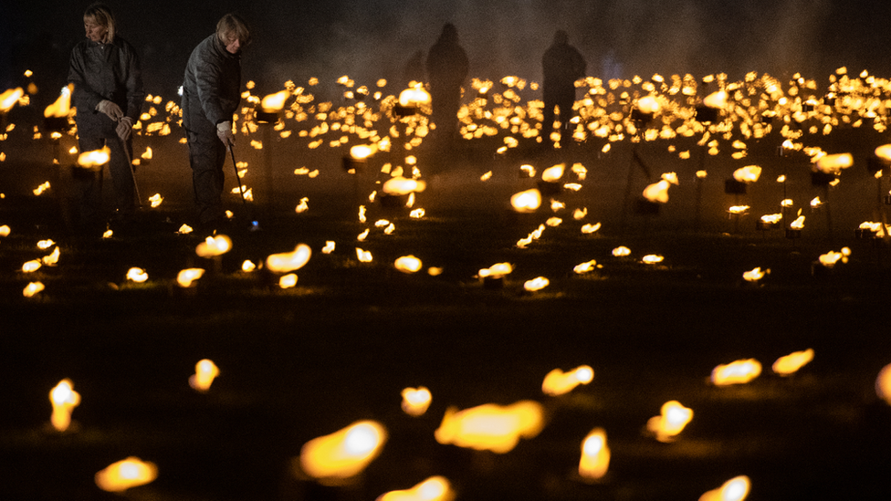 Volunteers light torches in the moat of the Tower of London