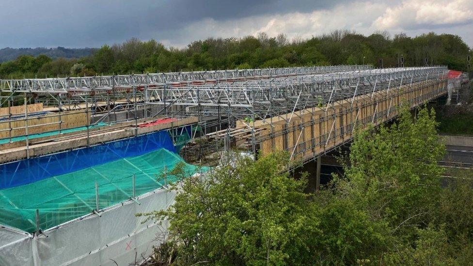 A bridge showing signs of renovation work being carried out as tarpaulin type coverings on parts