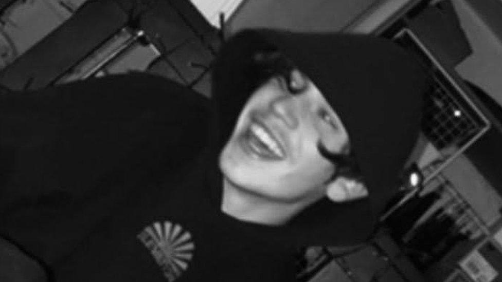 A black and white image of Samuel laughing while wearing a hoodie