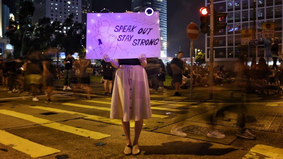 Protester holding up a sign 'speak out stay strong'