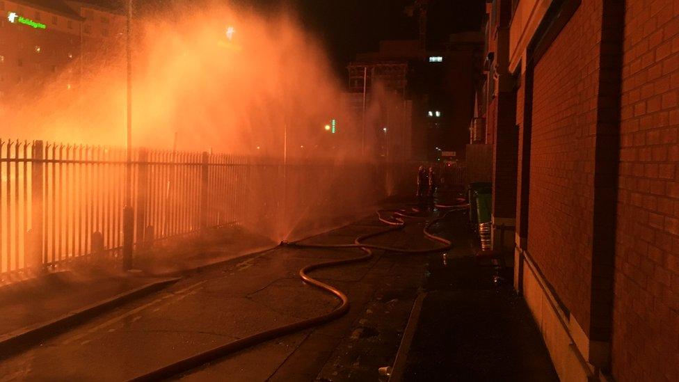 Firefighters worked to protect the apartment building in Belfast, hoses are pictured