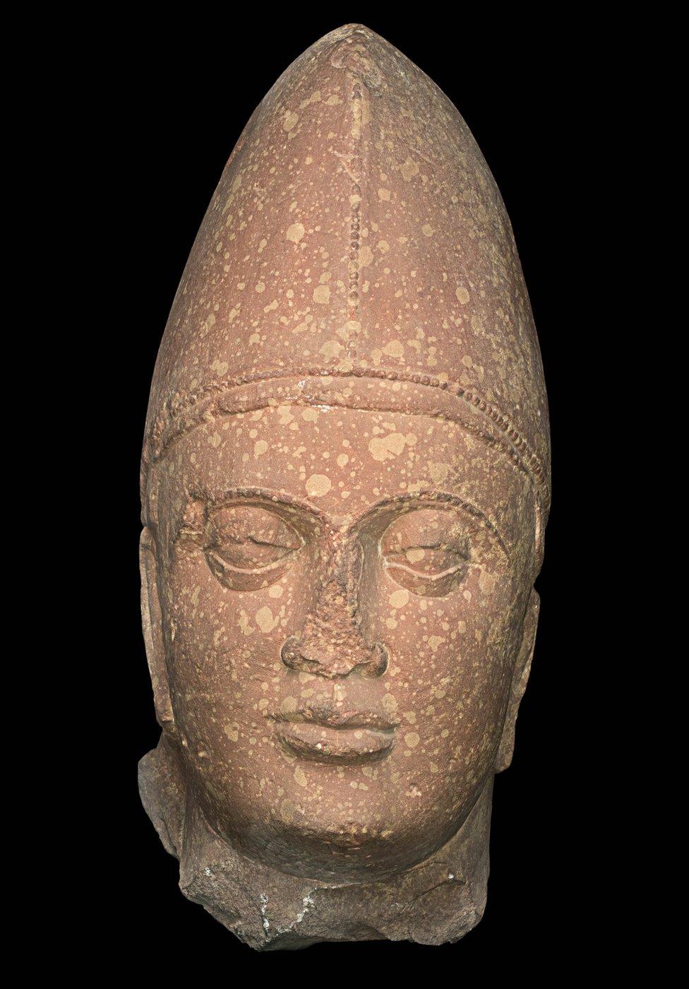 A sculpture of a Kushan king made of spotted red sandstone