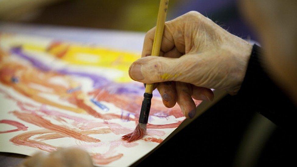 An elderly person painting