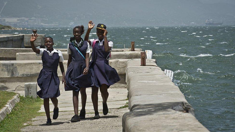 Schoolgirls wave while walking at Kingston harbour (pictured August 2012)