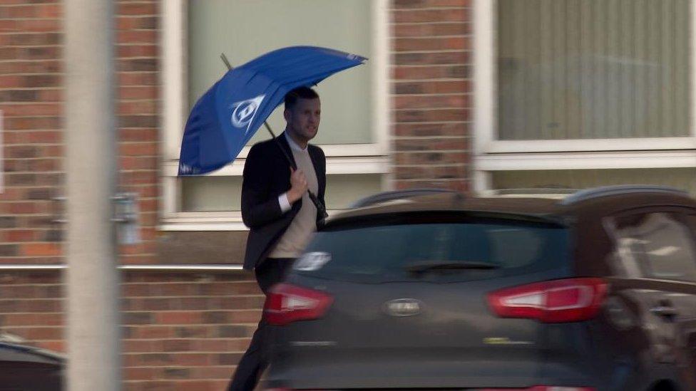 Daniel Reynolds outside Norwich Crown Court holding a blue umbrella