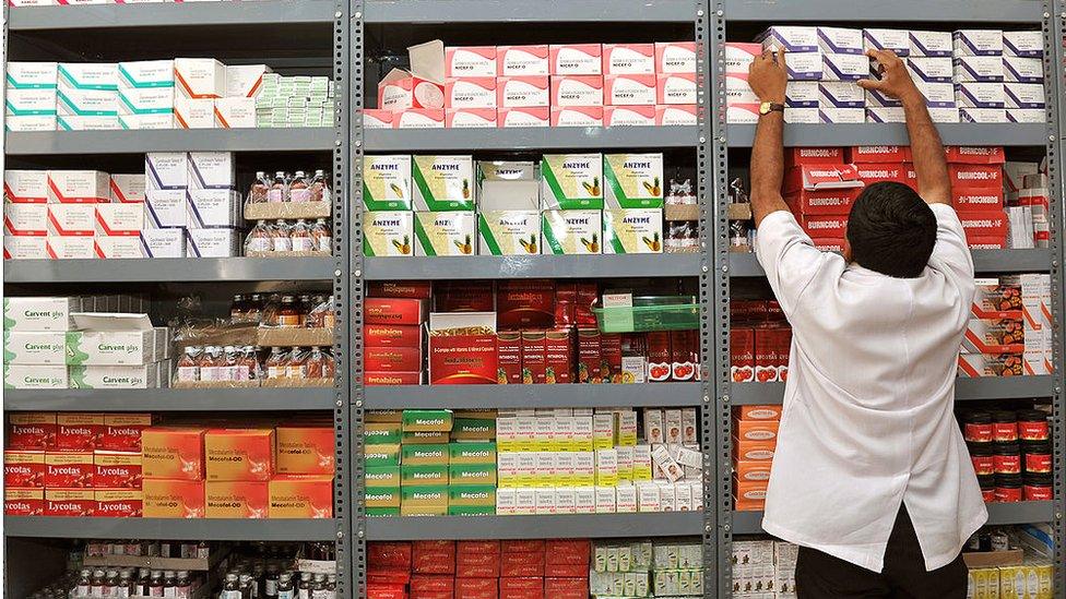 An Indian pharmacist pulls out a box of medicines from a shelf at a Generic Drug Store at the Victoria Hospital in Bangalore