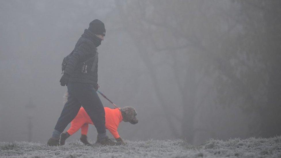 A dog walker makes their way through fog on a frosty morning at Primrose Hill in north London on December 11, 2022