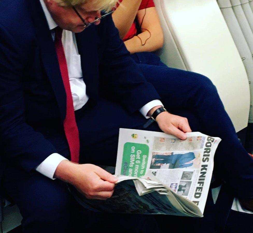 Boris Johnson reading a newspaper on which part of a headline is visible. It says: "Boris knifed..."