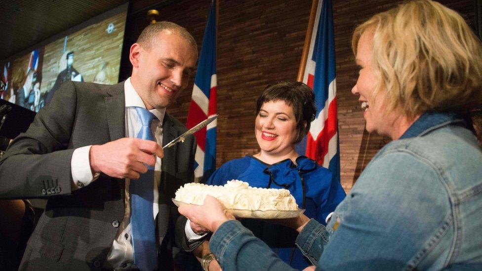 Gudni Johannesson (L) cuts a cake next to his wife Eliza Reid