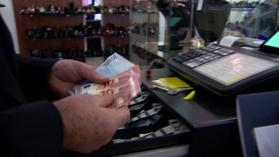 A cashier takes euro notes from a till