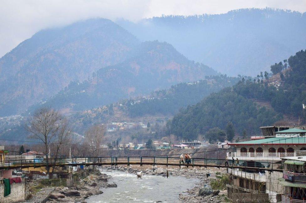 Pakistani residents walk on a bridge in the mountainous area of Balakot where the Indian Air Force launched a a strike on 26 February 2019.