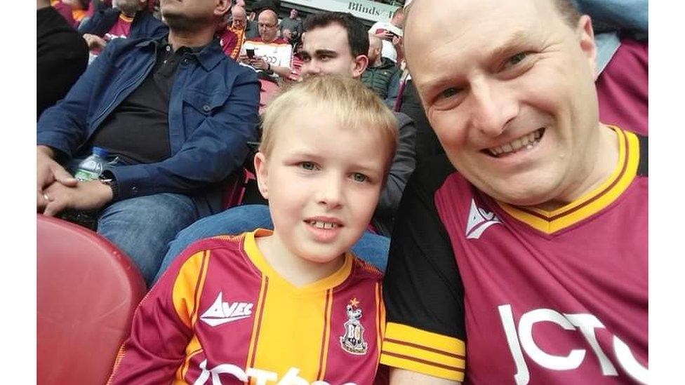 Image of a man and his son in Bradford City shirts in the crowd at a football match