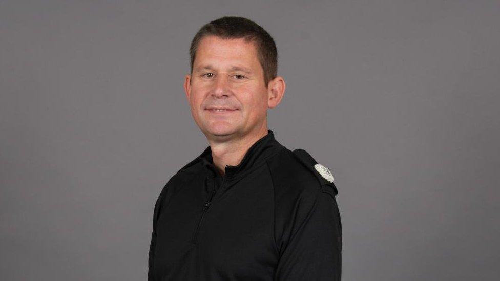 Man with short dark hair wearing a police uniform