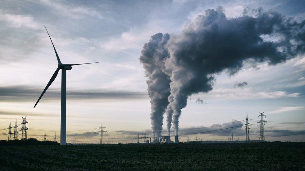 Windfarm in the foreground, factory spewing out gasses in the background.