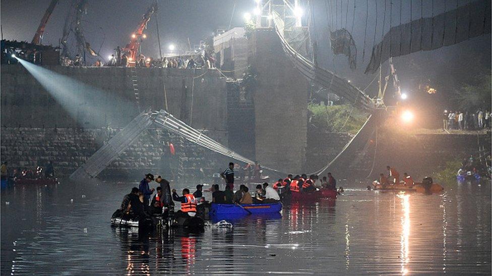 Indian rescue personnel conduct search operations after a bridge across the river Machu