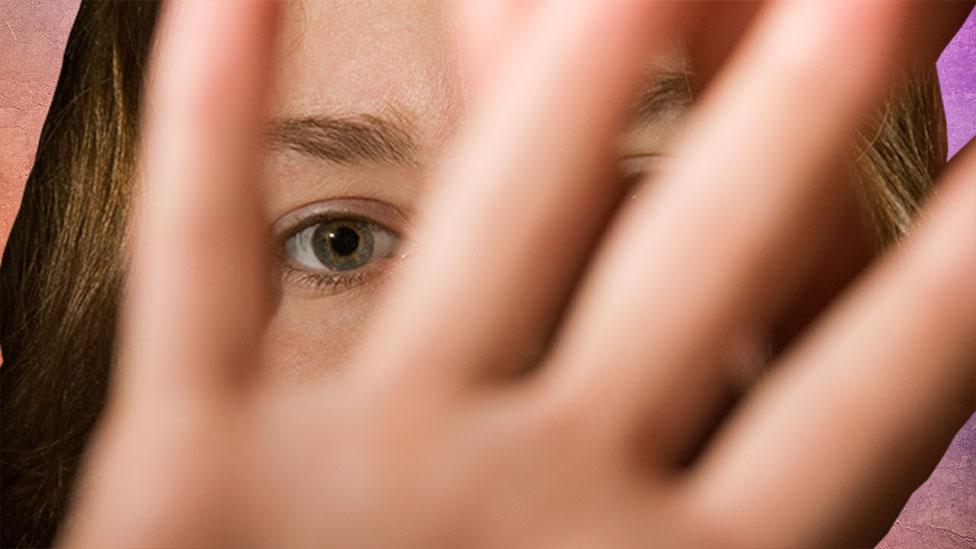 A woman holding a hand up in front of her face