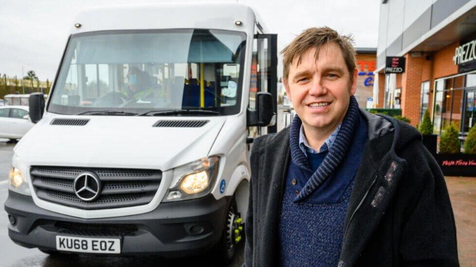 Mayor Nik Johnson standing in front of a bus