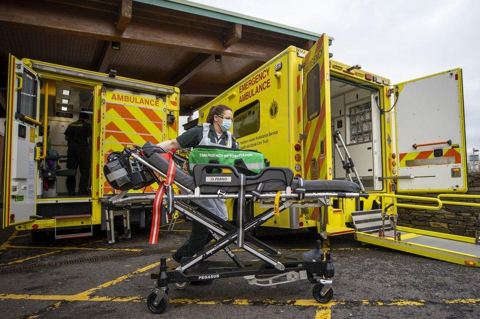 A paramedic working next to two ambulances