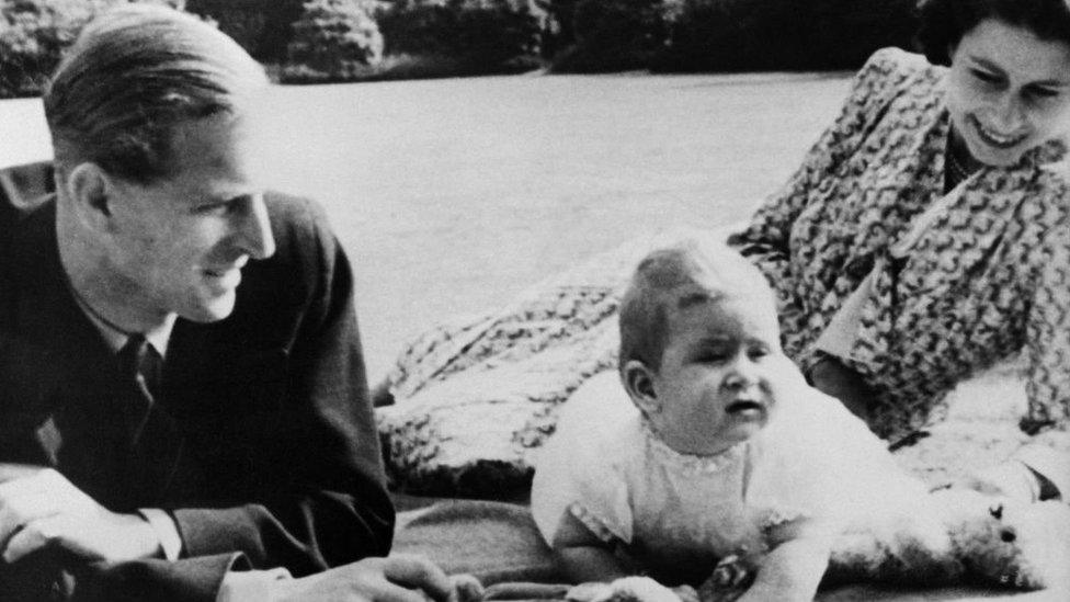 Princess Elizabeth and her husband Prince Philip, Duke of Edinburgh pose for a photo with a baby Prince Charles.