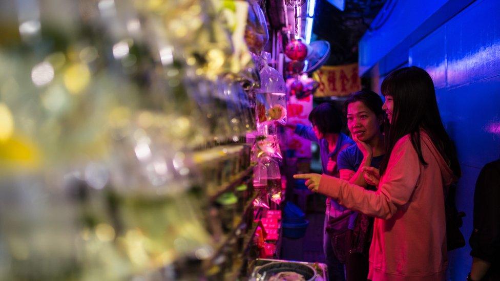 Customers browse fish in an alleyway street stall at the Mong Kok Goldfish Market in Hong Kong on November 1, 2015.