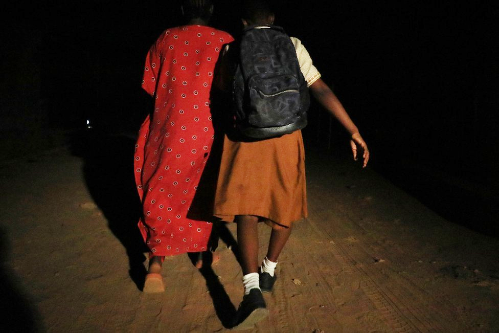 Schoolgirl Oluwapelumi Ogebere and her mother walking to a bus station early in the morning in Lagos, Nigeria