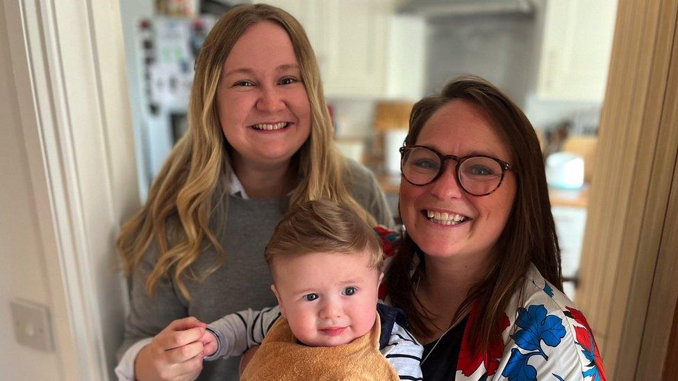 A baby is held by his two mums