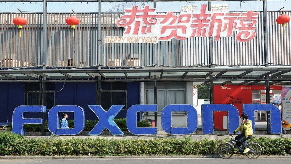 This picture taken on February 22, 2013 shows people walking past a Foxconn recruitment point in Shenzhen, south China's Guangdong province.