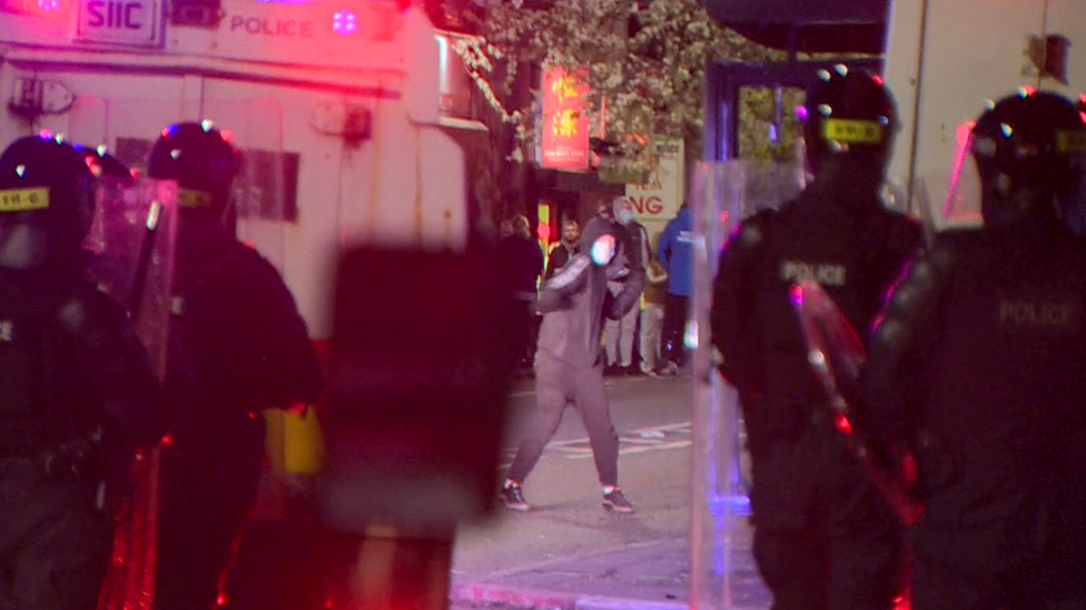 A young person prepares to throw a missile at police in riot gear in Belfast