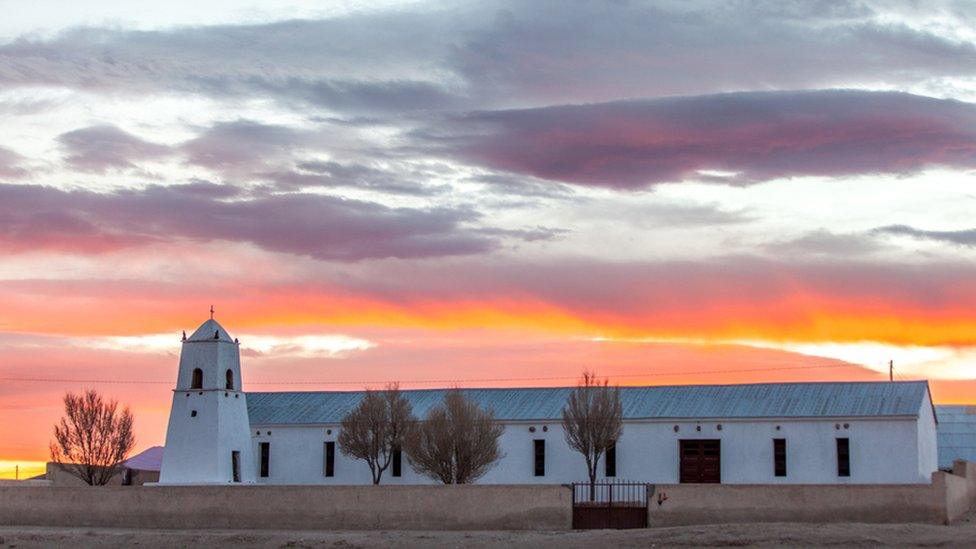 A building is seen in front of a sunset in the salt flat of Uyuni