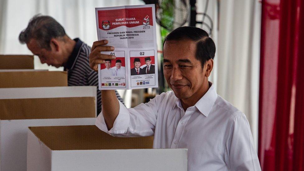 Indonesian President Joko Widodo shows his ballot paper at a polling station on April 17, 2019 in Jakarta, Indonesia