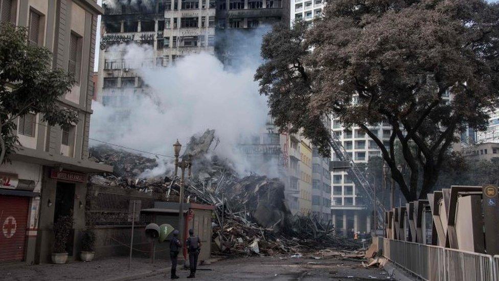 Police officers look as firefighters work to extinguish the fire in a building that collapsed after catching fire in Sao Paulo, Brazil, on May 1, 2018