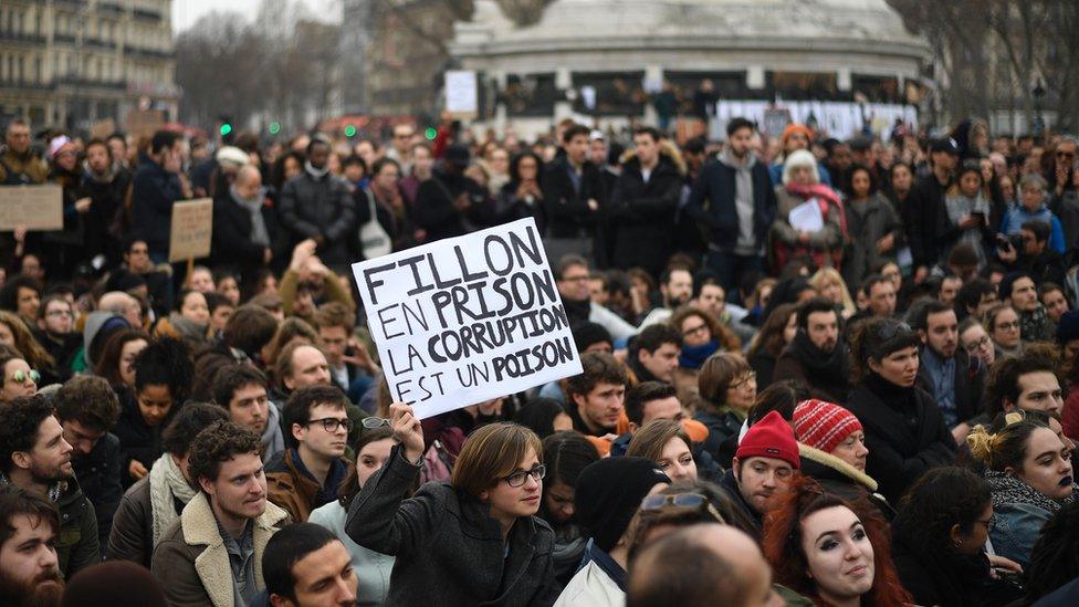 A man holds a placard reading 'Fillon to prison, corruption is a poison' a he sits in place de la Republique in Paris, on February 19, 2017