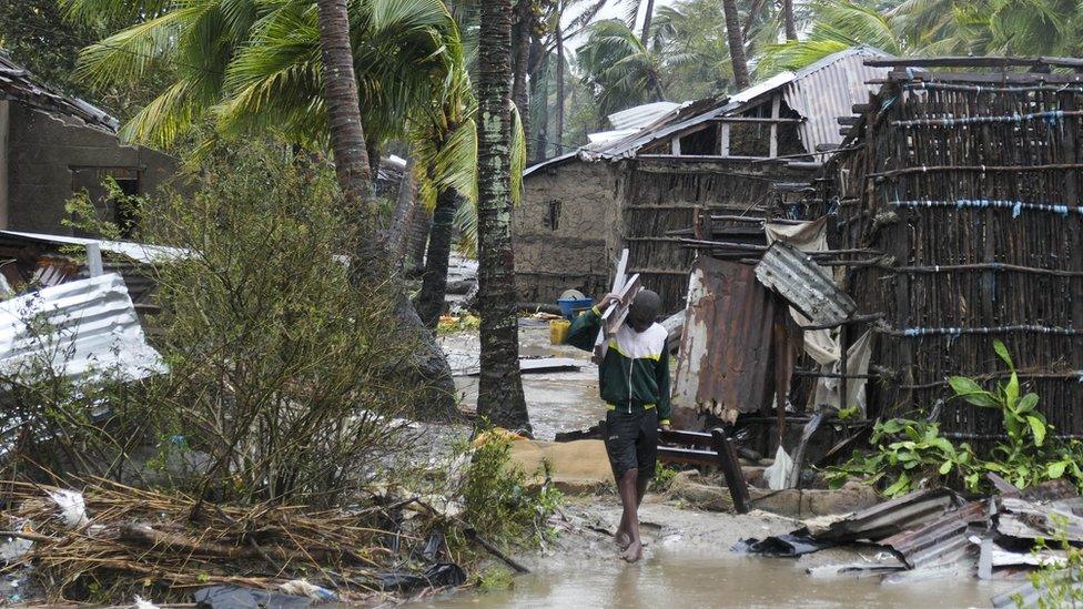 A man collects some wood on a flooded street