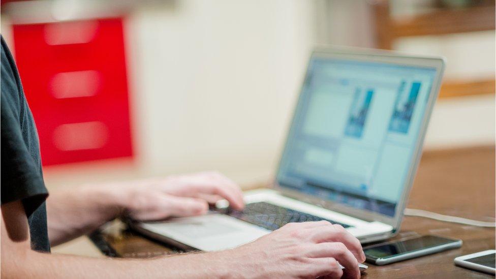 A man working outside the office on a laptop and mobile phone