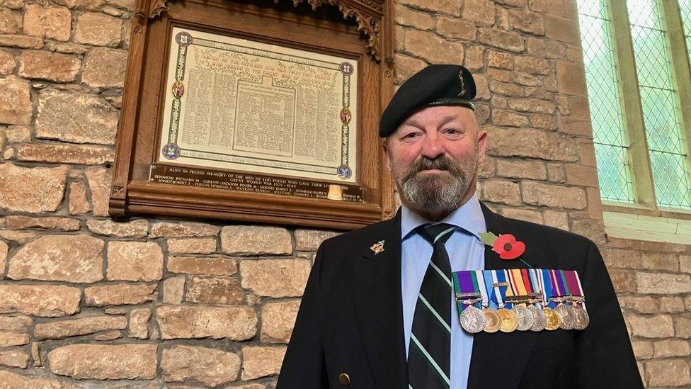 Colin Bell standing in front of the roll of honour at St Mary's Church in Dymock