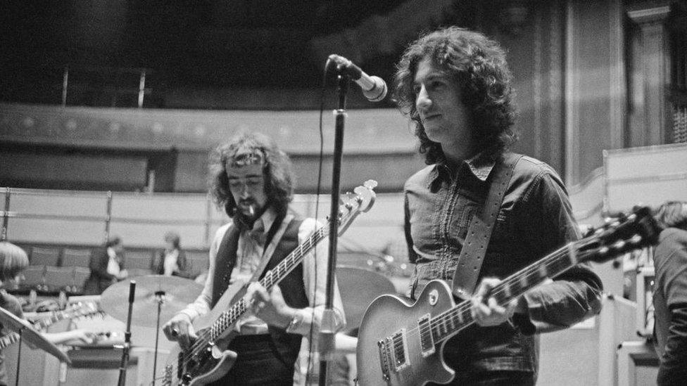 A black and white photo of Peter Gren playing guitar and John McVie playing bass