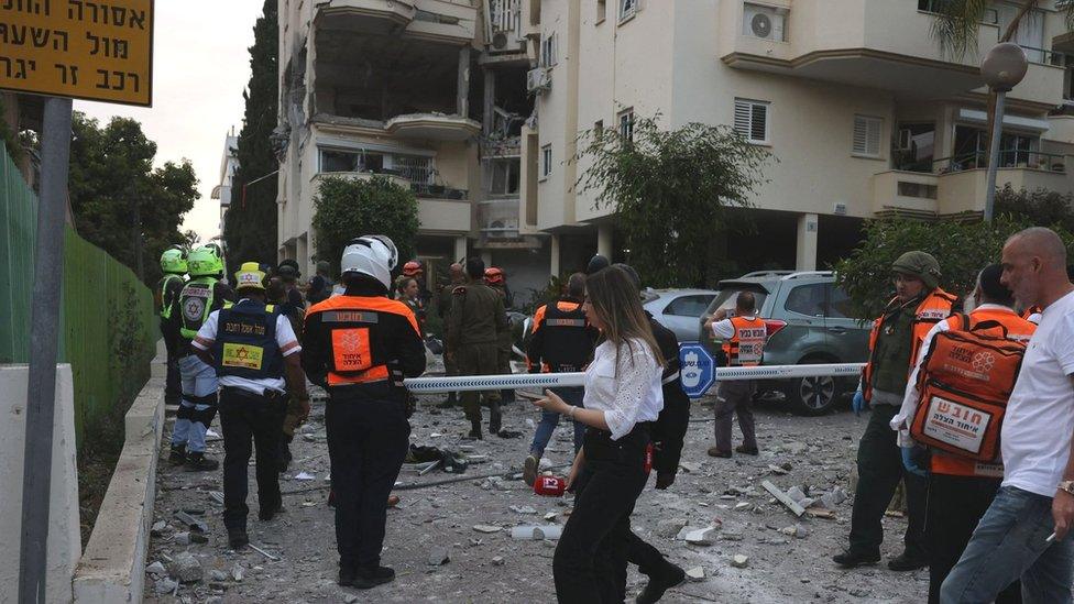 Israeli first responders work near an apartment building in Rehovot, central Israel, that was hit by a rocket fired from the Gaza Strip (11 May 2023)