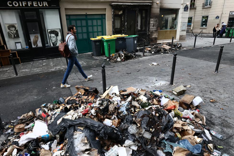 A man walks past a burnt store and damages in a street the day after clashes during protests over French government's pension reform in Paris, France, March 24, 2023.